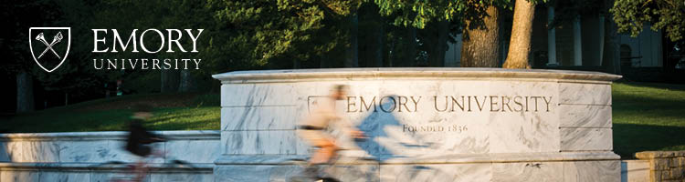 wall at emory entrance with blurred bicyclist riding in front of it 